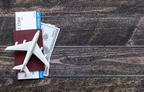 Avión de juguete, billete de avión, tarjetas de crédito, dólares y pasaporte en mesa de madera. Concepto de viaje - Foto, imagen