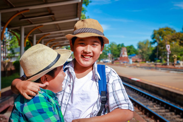 Dos chicos viajan para pararse y esperar el tren en la estación de Lopburi, Tailandia. - Foto, imagen