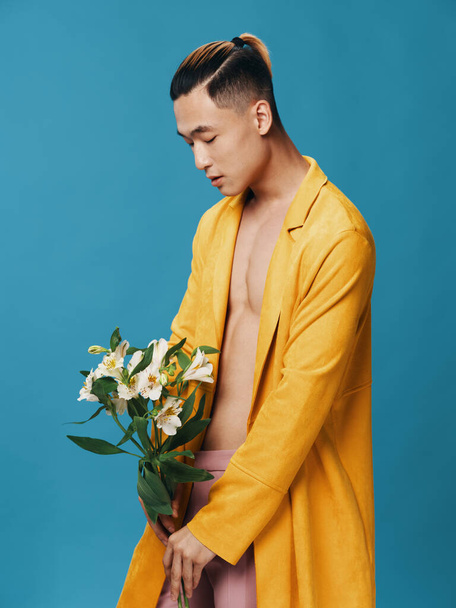 Side view of a gentleman in a yellow coat with a bouquet of white flowers on a blue background - Fotoğraf, Görsel