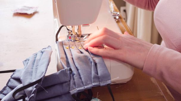 Mascarilla de algodón de coser con una máquina de coser para el brote de coronavirus. - Foto, imagen
