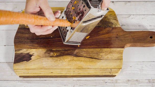 Тертая органическая оранжевая морковь на доске для резки древесины. - Фото, изображение