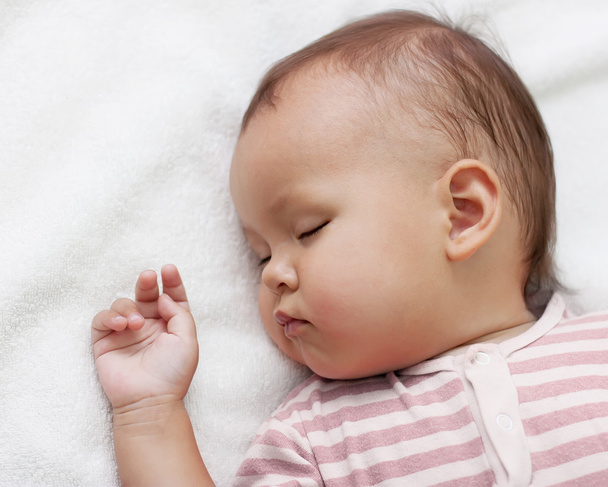 klein meisje slapen op een witte handdoek - Foto, afbeelding