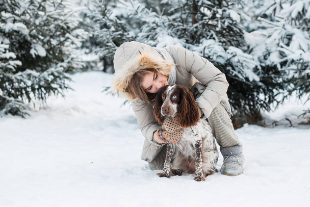 Happy woman hugging with chocolate spaniel in winter forest. close up. - Fotoğraf, Görsel