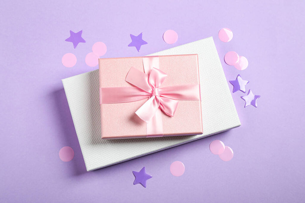 Beautiful gift boxes and confetti on violet background, flat lay - Foto, imagen