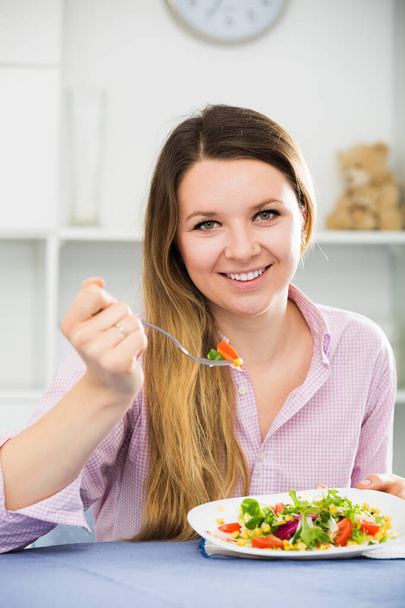 Jeune fille souriante dégustant une salade verte savoureuse - Photo, image