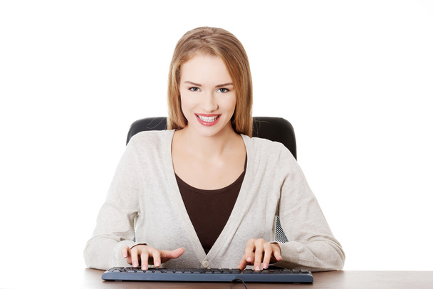 Beautiful casual woman student is writing on keyboard. - Фото, зображення