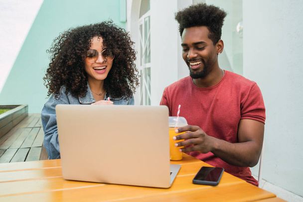 Two Afro friends using laptop at a cafeteria. - Fotó, kép