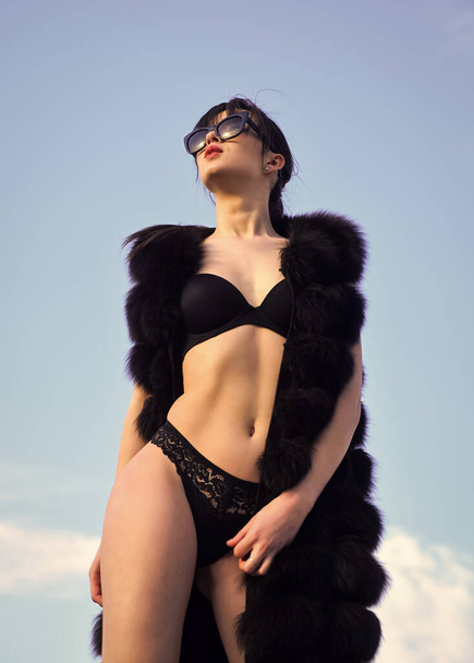 Hey cutie. sexy woman wear erotic lingerie and fur waistcoat. sensual girl in summer sunglasses on sky background. female beauty and fashion. woman has fit and slim body. luxury and success - Fotografie, Obrázek