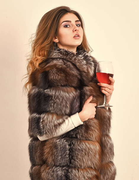 Lady fashion model curly hairstyle enjoy elite wine. Wine culture concept. Reasons drink red wine in wintertime. Woman drink wine. Girl fashion makeup wear fur coat hold glass alcohol. Elite leisure - Foto, Imagem