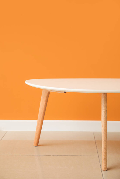 Wooden table near color wall in room - Foto, Bild