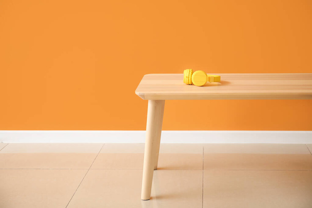 Sluchátka na dřevěném stole v blízkosti barevné stěny na pokoji - Fotografie, Obrázek