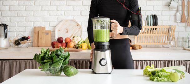 Alimentação saudável, conceito de dieta. Jovem loira sorrindo mulher fazendo smoothie verde em casa cozinha - Foto, Imagem