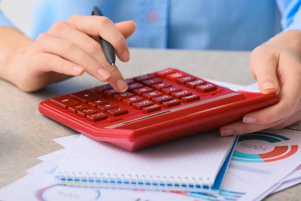 Vrouwelijke accountant met rekenmachine aan het werk, close-up - Foto, afbeelding