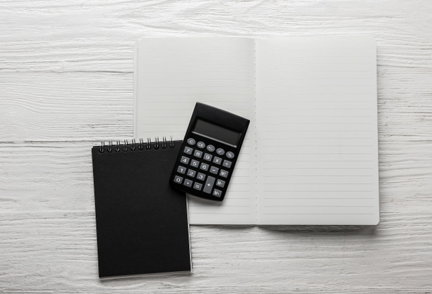 Nowoczesny kalkulator i notebooki na drewnianym tle - Zdjęcie, obraz