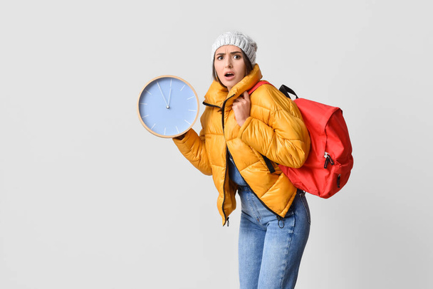 Stressed female student with clock on grey background - Fotoğraf, Görsel