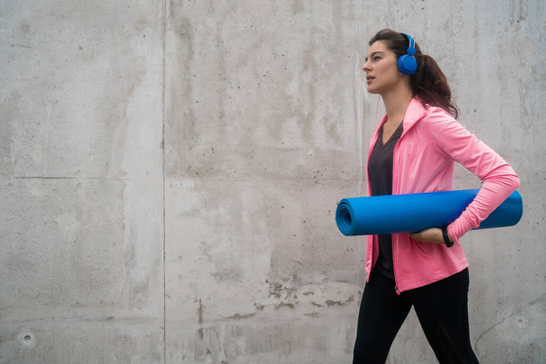 Athletic woman holding a training mat. - Фото, зображення
