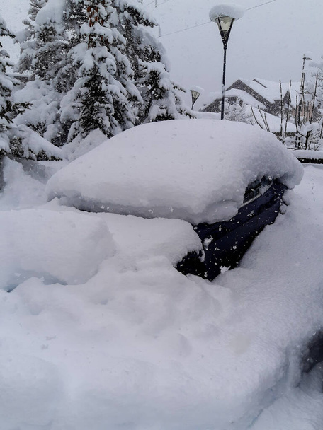 coche azul debajo de una pila de nieve estacionado en la calle en el banco de nieve después de ventisca - Foto, Imagen