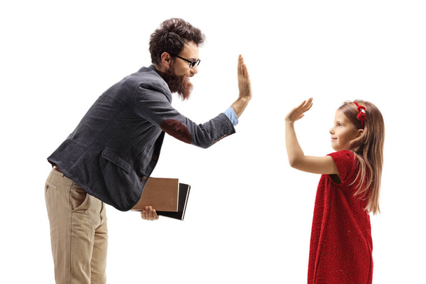 Smiling bearded man holding books and gesturing high-five with a little girl isolated on white background - Foto, Imagem