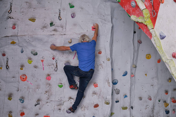 Hombre mayor profesional escalando en una pared de escalada artificial. Concepto de deportes extremos. - Foto, Imagen