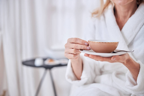 Female enjoying delicious cup of tea in spa resort hotel - 写真・画像