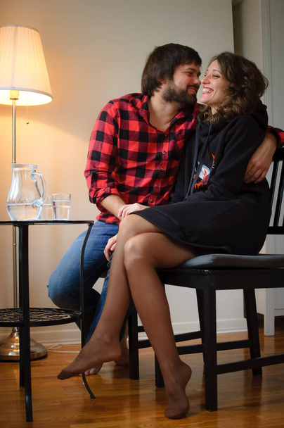 Przystojny brodaty mężczyzna ubrany w lambersexual stylu ubrania jest przytulanie jej młoda kobieta w czarny ciepły ubrany podczas uroczystości St Walentynki - Zdjęcie, obraz