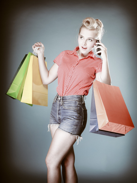 Pinup girl with shopping bags calling on the phone - 写真・画像