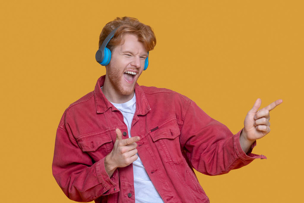 Young ginger man listening to music and feeling entertained - Foto, imagen