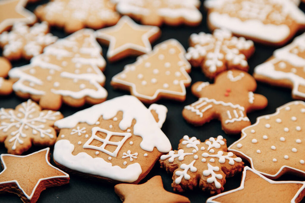 Winter holiday pattern-a set of gingerbread, the layout of the pattern on a dark background. cookies in the form of a house, a christmas tree, a person, a star decorated with icing. - Foto, imagen