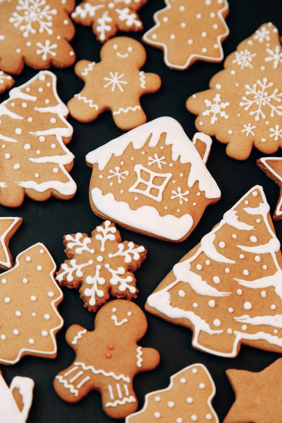 Winter holiday pattern-a set of gingerbread, the layout of the pattern on a dark background. cookies in the form of a house, a christmas tree, a person, a star decorated with icing. - Foto, imagen