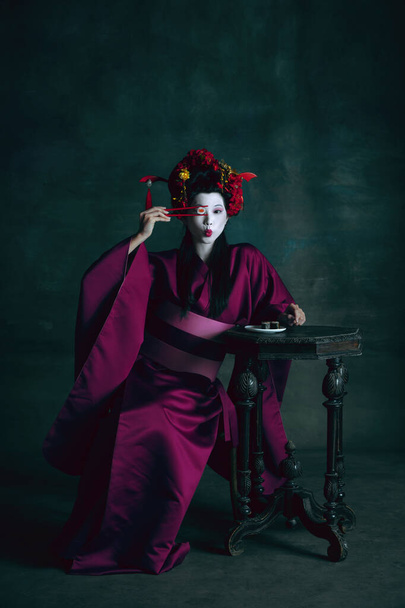 Jeune femme japonaise comme geisha sur fond vert foncé. Style rétro, comparaison des époques concept. - Photo, image
