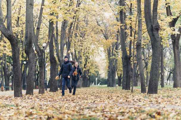 menina adolescente e menino correndo pelo parque e gosta de outono, bela natureza com folhas amarelas - Foto, Imagem