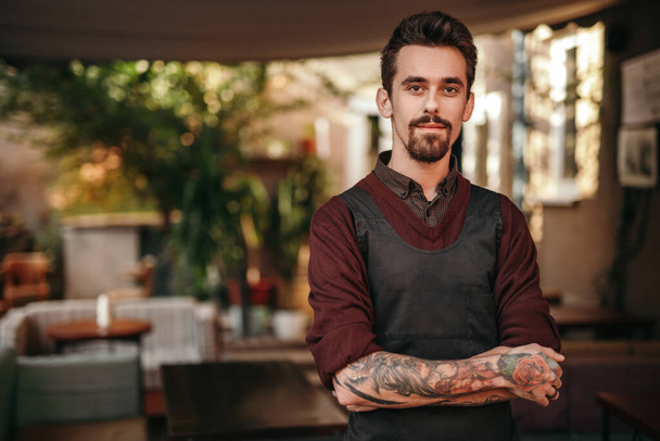 Confident tattooed barista in cozy cafe - Photo, image