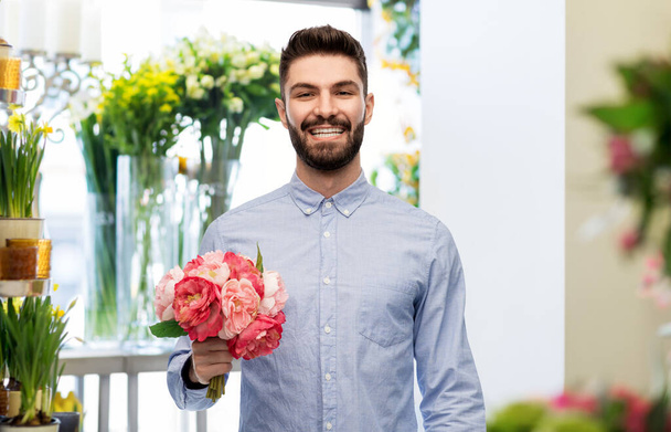 happy smiling man with peonies at flower shop - Фото, зображення