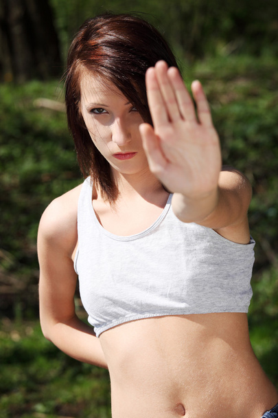 Young woman in white top showing sign stop. - 写真・画像