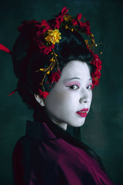 Young japanese woman as geisha on dark green background. Retro style, comparison of eras concept. - Foto, Bild
