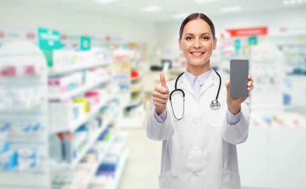 doctor with smartphone shows thumbs up at pharmacy - Fotografie, Obrázek