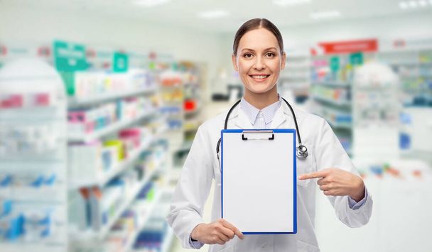 happy female doctor with clipboard at pharmacy - Foto, afbeelding