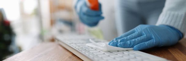 Female hands in rubber gloves wiping keyboard with antiseptic napkin in office - Photo, Image