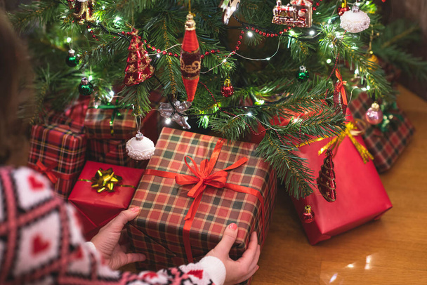 Woman putting gift box under christmas tree. Presents for family.  - Foto, Imagen