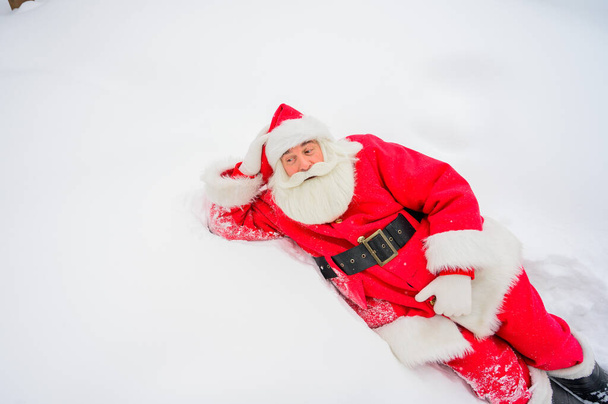 Happy santa claus lying in the snow and fooling around - Φωτογραφία, εικόνα