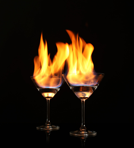 Bril met brandende alcohol op zwarte achtergrond - Foto, afbeelding