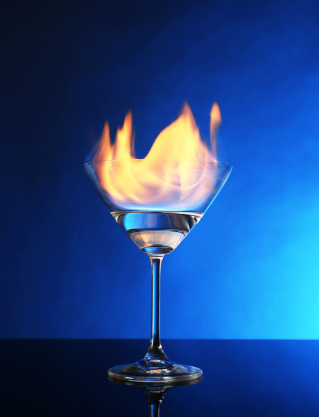 Glass with burning alcohol on blue background - Photo, Image