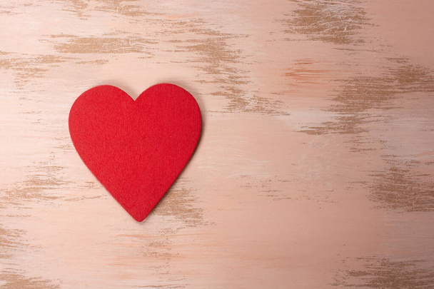 A closeup shot of a felt heart on a wooden background - Valokuva, kuva