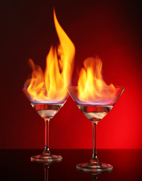 Glasses with burning alcohol on red background - Фото, зображення