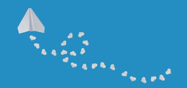 χάρτινο αεροπλάνο και λευκές καρδιές σε μπλε φόντο. αγάπη ταξίδια ή έννοια διακοπών για την ημέρα του Αγίου Βαλεντίνου. banner, αντίγραφο χώρου - Φωτογραφία, εικόνα