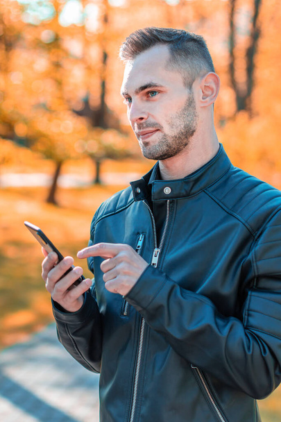 Handsome Guy Using Smartphone at Autumn Park - Zdjęcie, obraz