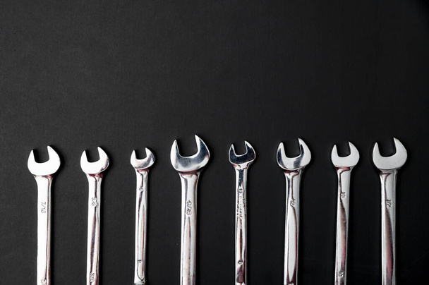 A top view of different combination wrenches on a black background - Foto, immagini