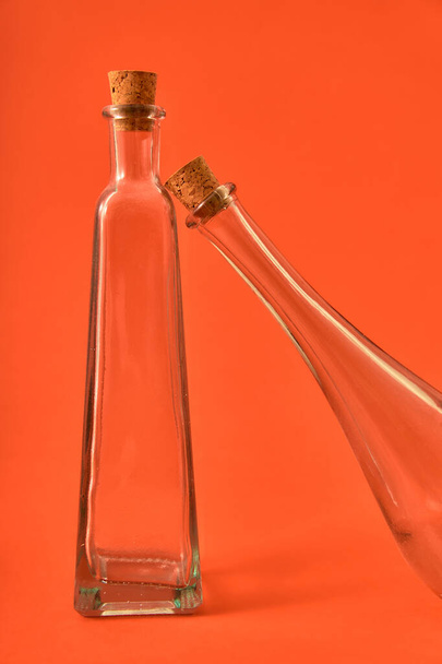 Empty glass bottle with original shapes on a solid neutral colored background. Studio lighting. Concept for advertising with space for sign or edition - Foto, Imagen