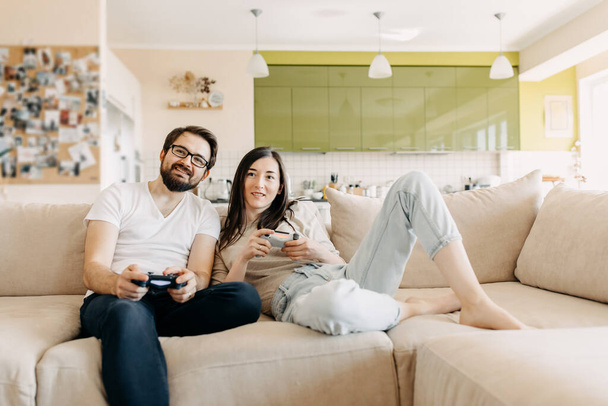 όμορφο νεαρό ζευγάρι που παίζει βιντεοπαιχνίδια μαζί στο σπίτι - Φωτογραφία, εικόνα