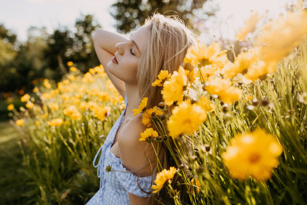黄色の花と緑の草原の夏のドレスの美しい若い女性の肖像画 - 写真・画像